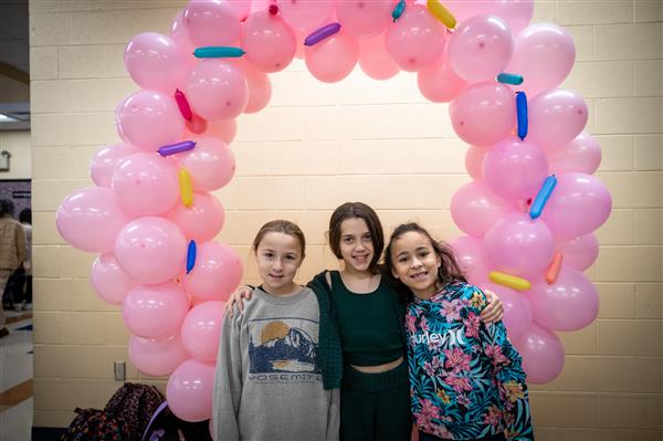 three girls in front of giant pink donut